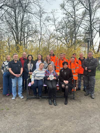 Quasselbank Heiligensee: hinten von links Vorstandsmitglieder der Seniorenfreizeiteinrichtung Heiligensee, Einsamkeitsbeauftragte Katharina Schulz, Leiterin des Fachbereichs Senioren Sanja Cica, stellv. Leitung Fachbereich Senioren Nadine Zenk, stellv. Ausbildungsleitung Alvaro Foppe, Auszubildende des Stra�en- und Gr�nfl�chenamtes, Ausbildungsleiter Devon Polte.  Auf der Bank: Vorstandsmitglieder der Seniorenfreizeiteinrichtung Heiligensee